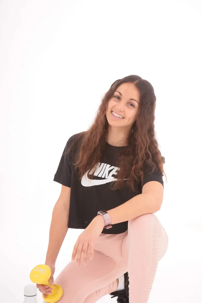 Lucía, de Génesis, sonriendo con unas mancuernas